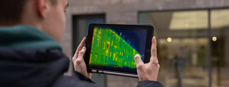 Junger Mann hält ein Tablet mit einer Wärmebildkamera