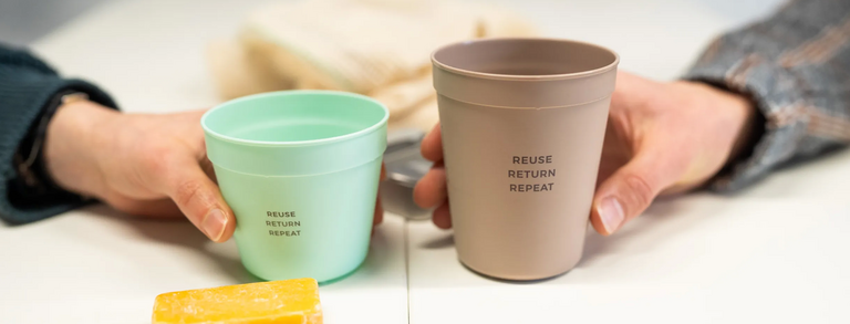 Hände halten widerverwendbare Kaffebecher.