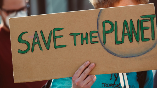 Plakat in der Hand einer Person mit der Aufschrift "Save the Planet"