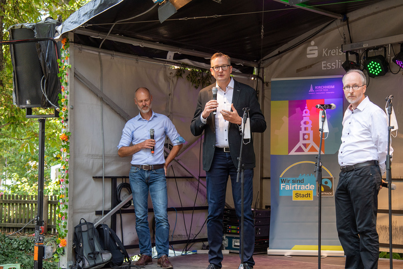 Während der Nachhaltigkeitstage in Kirchheim unter Teck stehen auf einer Bühne drei Männer, von welchen einer gerade einen Vortrag hält.